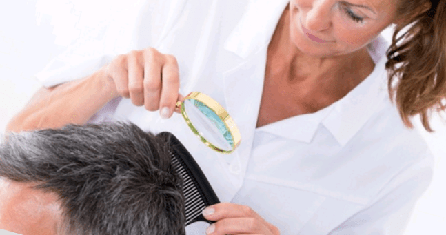 doctor examines psoriasis on the head